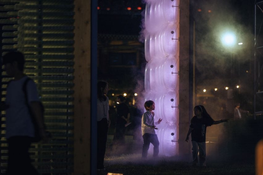 Kids playing by illuminated artwork