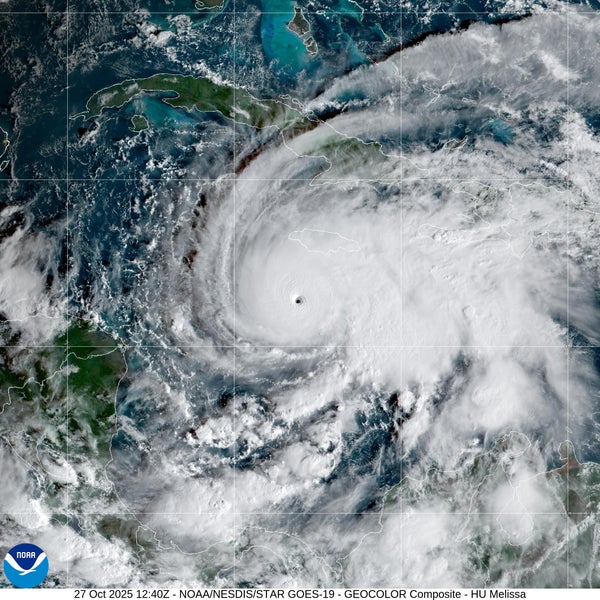 White swirl of the clouds of a hurricane with a distinct central eye against the blue and green backgrounds of the Caribbean Sea and islands