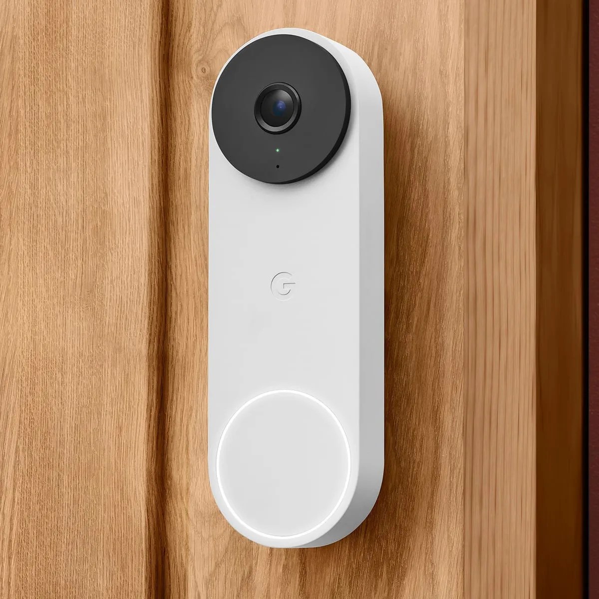 White and black Google video doorbell mounted on a wooden door.