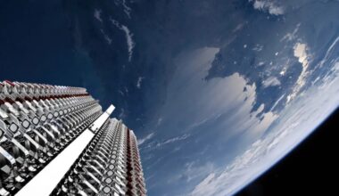 view from the upper stage of a rocket looking down at its closely packed satellite payload and Earth in the background
