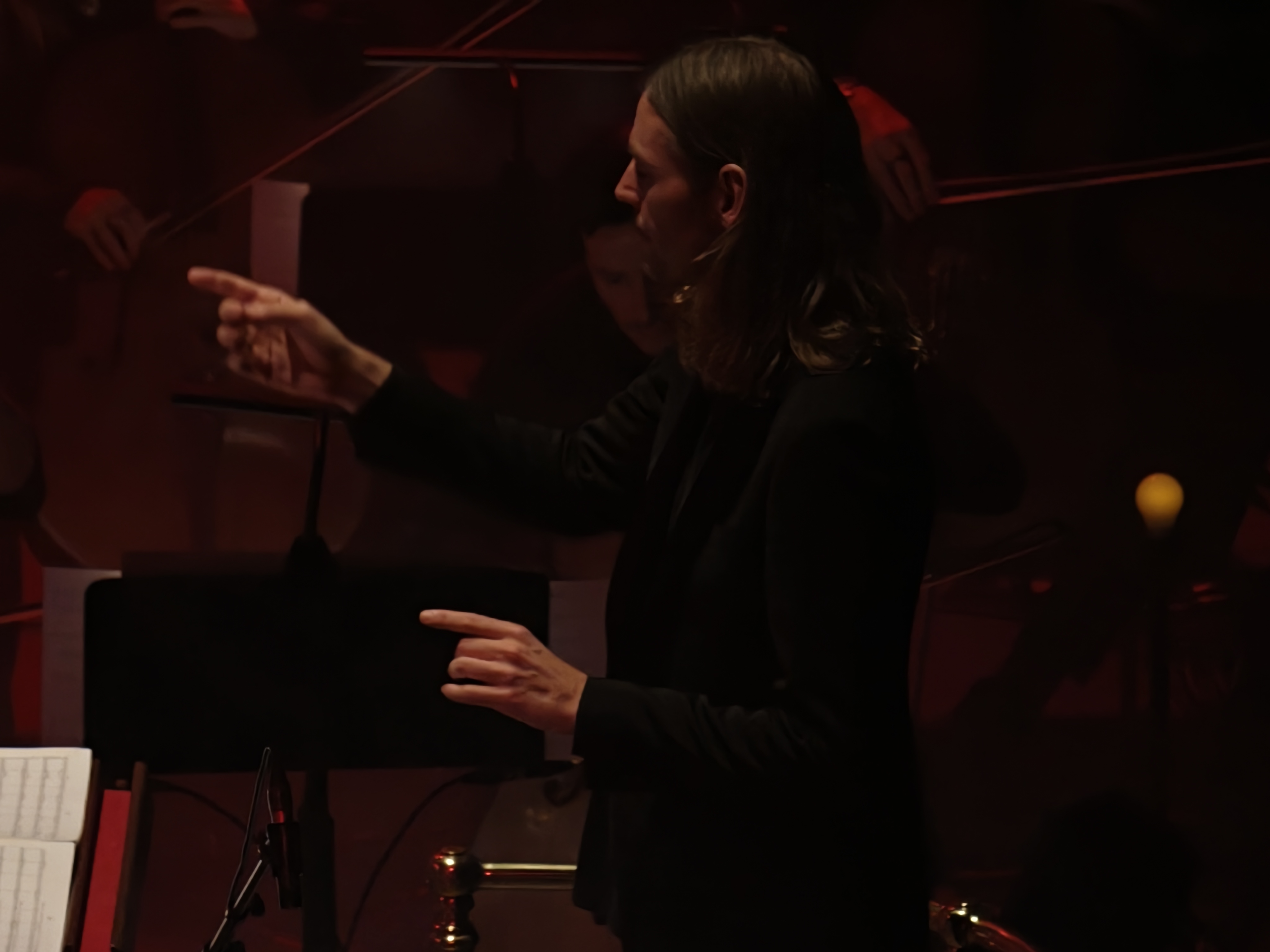 A conductor pointing to an orchestra