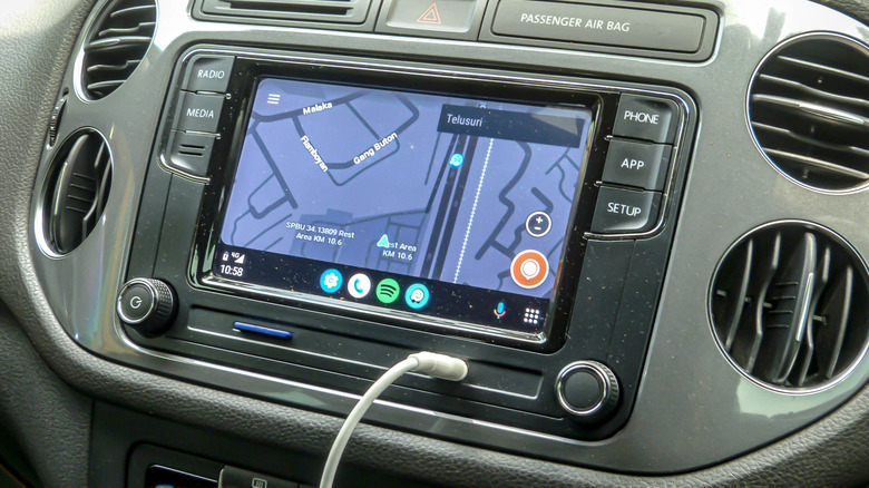 An infotainment screen with a USB cable plugged into its auxiliary port, the screen is displaying a map