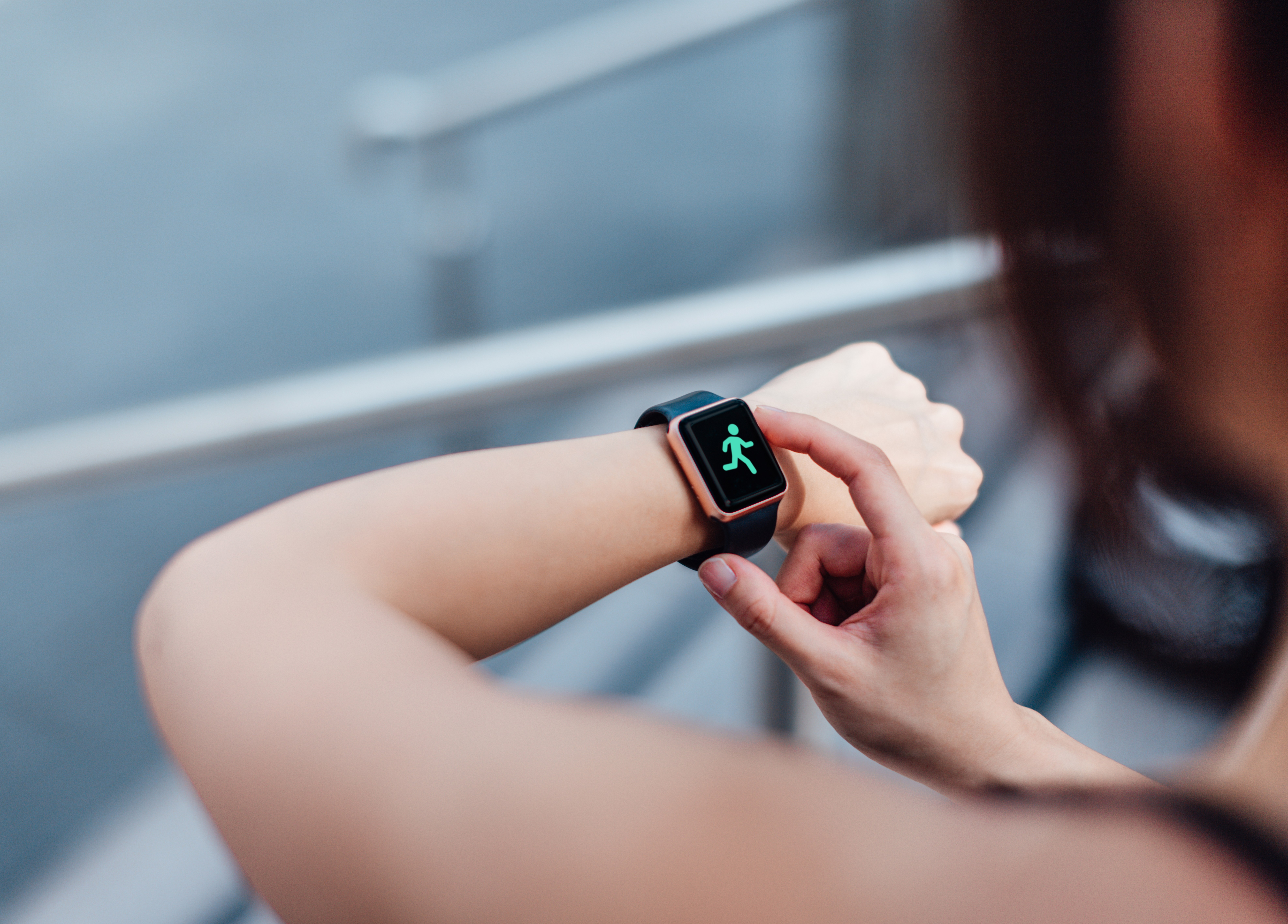 Over-the-shoulder view of a young woman using her smart watch for tracking workout.