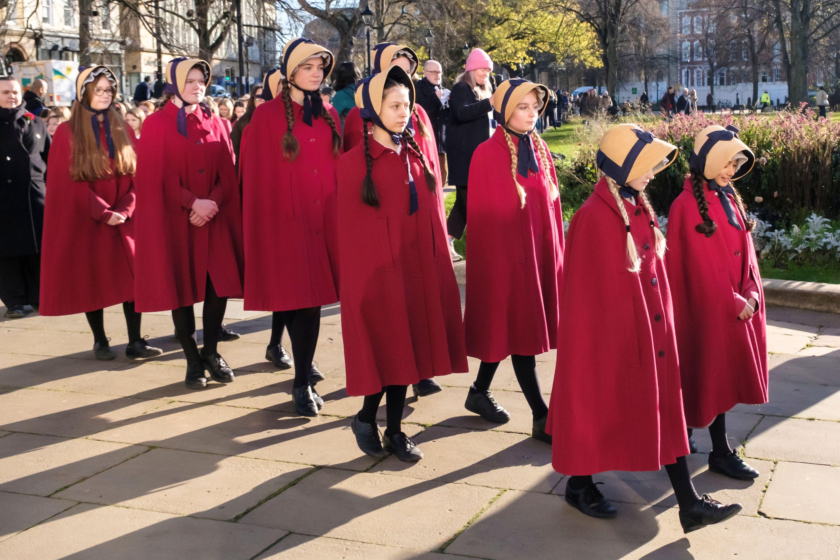 Girls in traditional red dresses and bonnets leading the annual Red Maids Founders Commemoration Day procession.