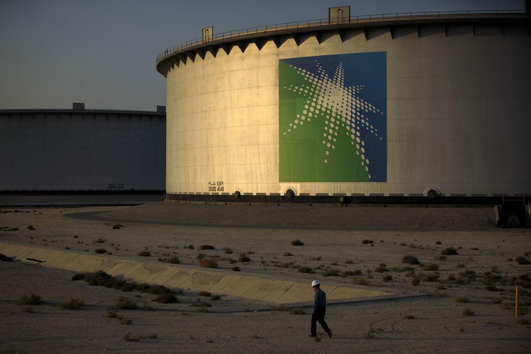 An employee walks past crude oil storage tanks at the Juaymah Tank Farm, part of Saudi Aramco's Ras Tanura complex in Ras Tanura, Saudi Arabia, in 2018.