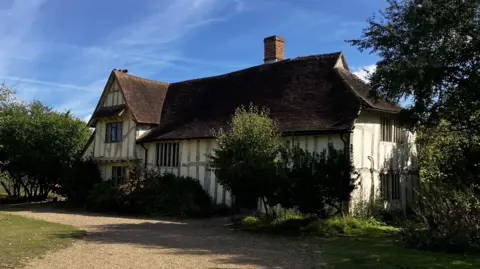 Matt Marvel/BBC Valley Farm in Flatford today. It is a medieval building with wooden beams on its exterior and wooden-framed windows. 