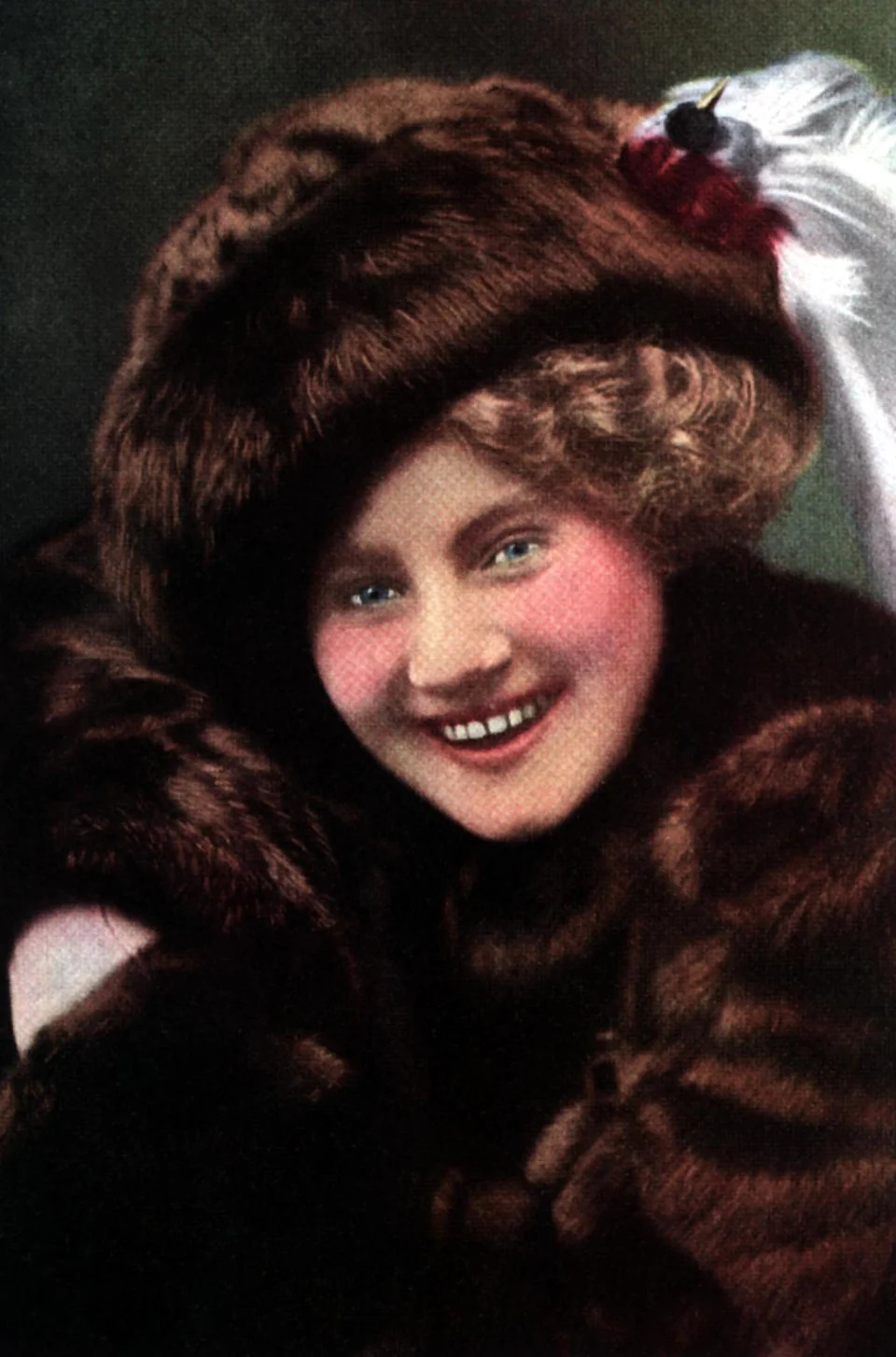 Lawrencee in vintage attire with fur hat and coat, smiling at the camera. Hair styled with soft curls peeking from under the hat