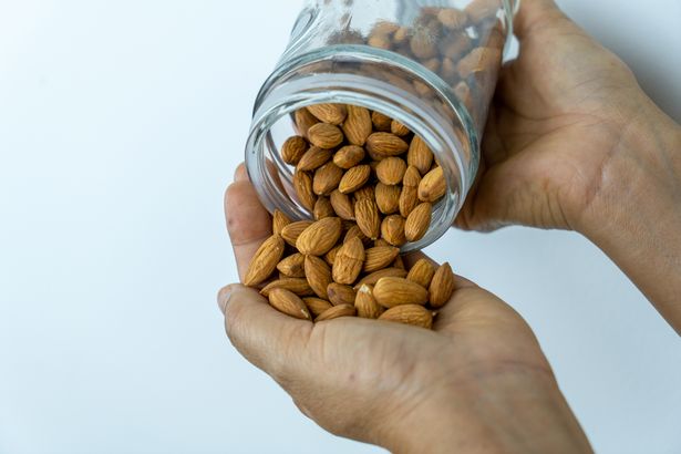 A woman pour almond from bottle to her hand
