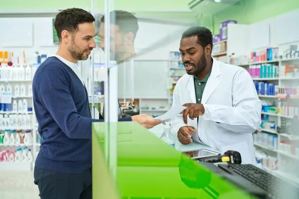 Male pharmacists talking with customer in pharmacy