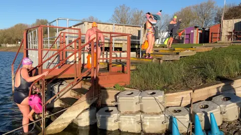 BBC Four people getting in or out of the lake, with people drying themselves off or climbing out of it.
