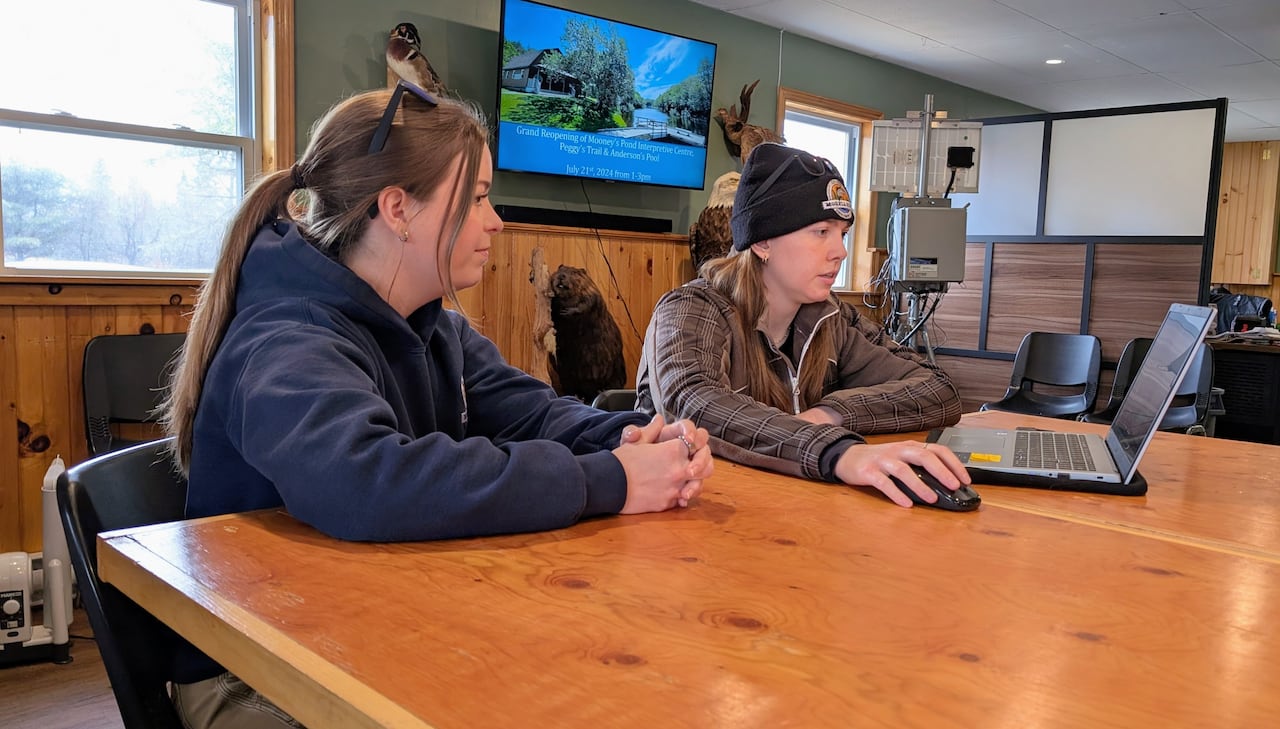 Two young women looking at trail cam photos on a laptop.