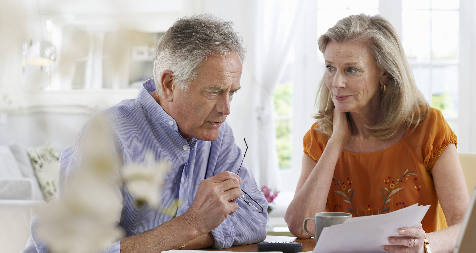 Mature couple with bills sitting at dining table in house