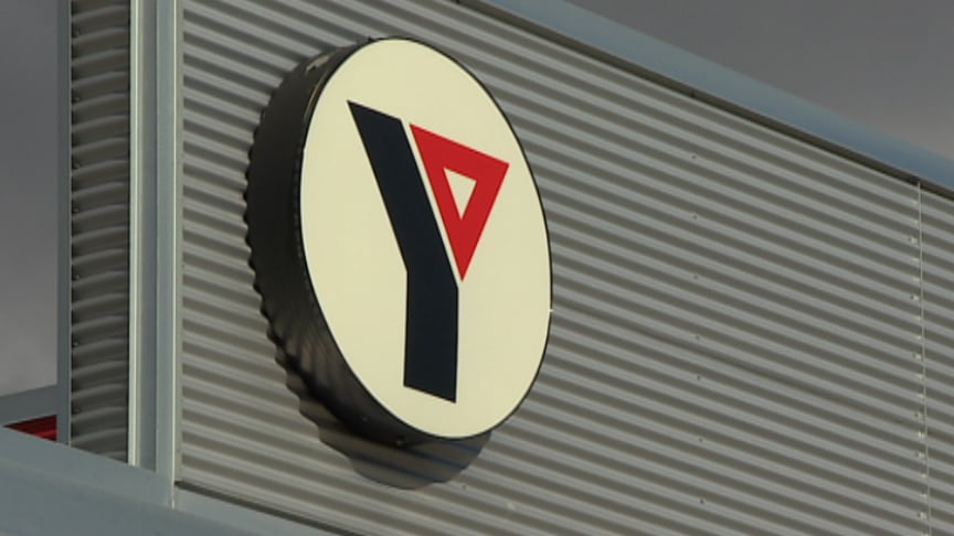 A closeup photo shows a sign with a stylized "Y" logo on a building.