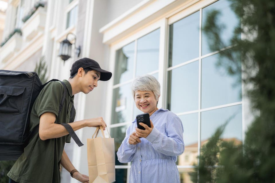 Senior woman receiving food order from a delivery man