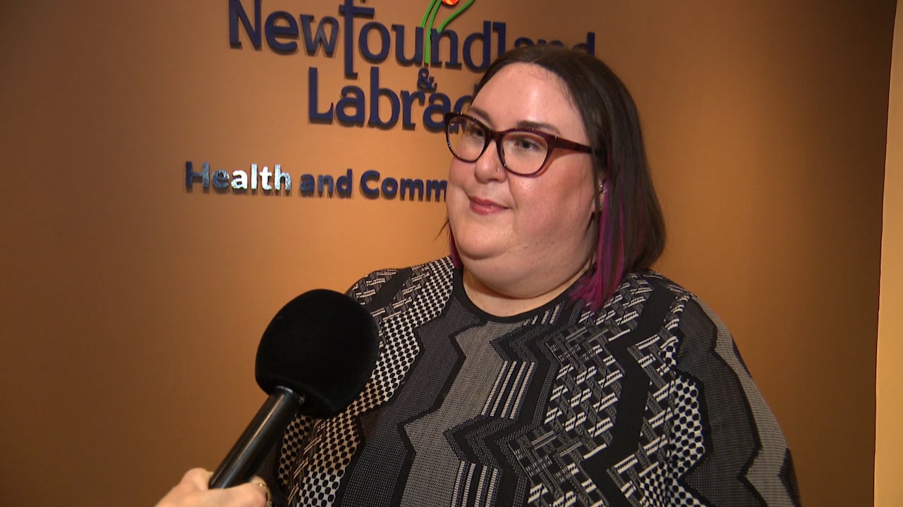 A smiling woman stands in front of a microphone.