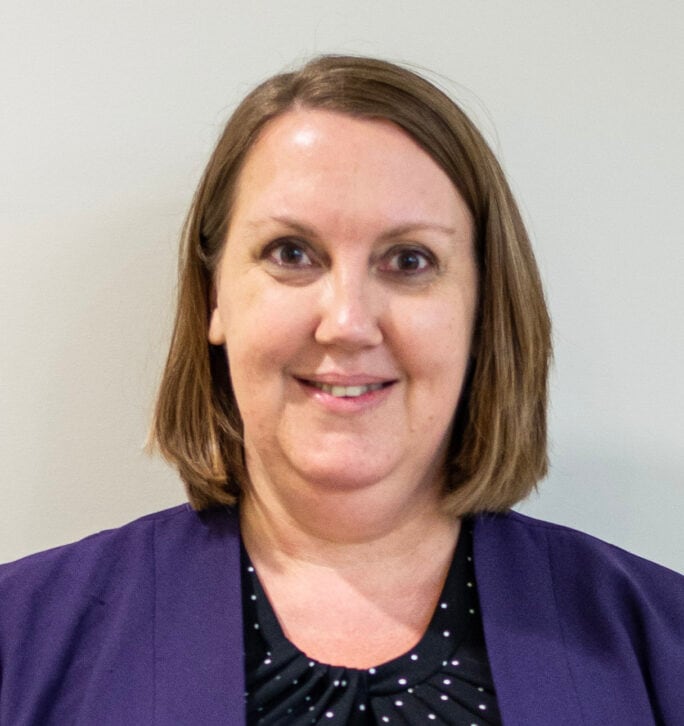 A woman with short hair wearing a purple sweater.