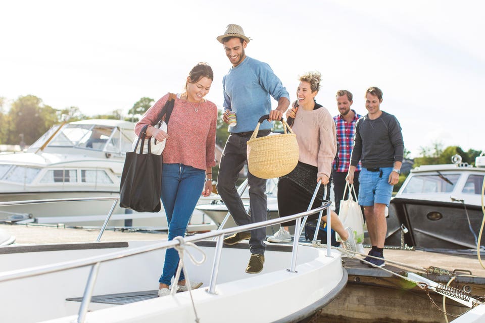 Friends boarding yacht against sky