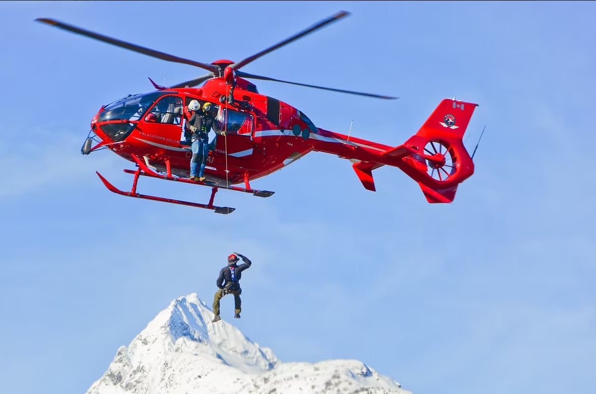 A person hangs from a long line from a helicopter.