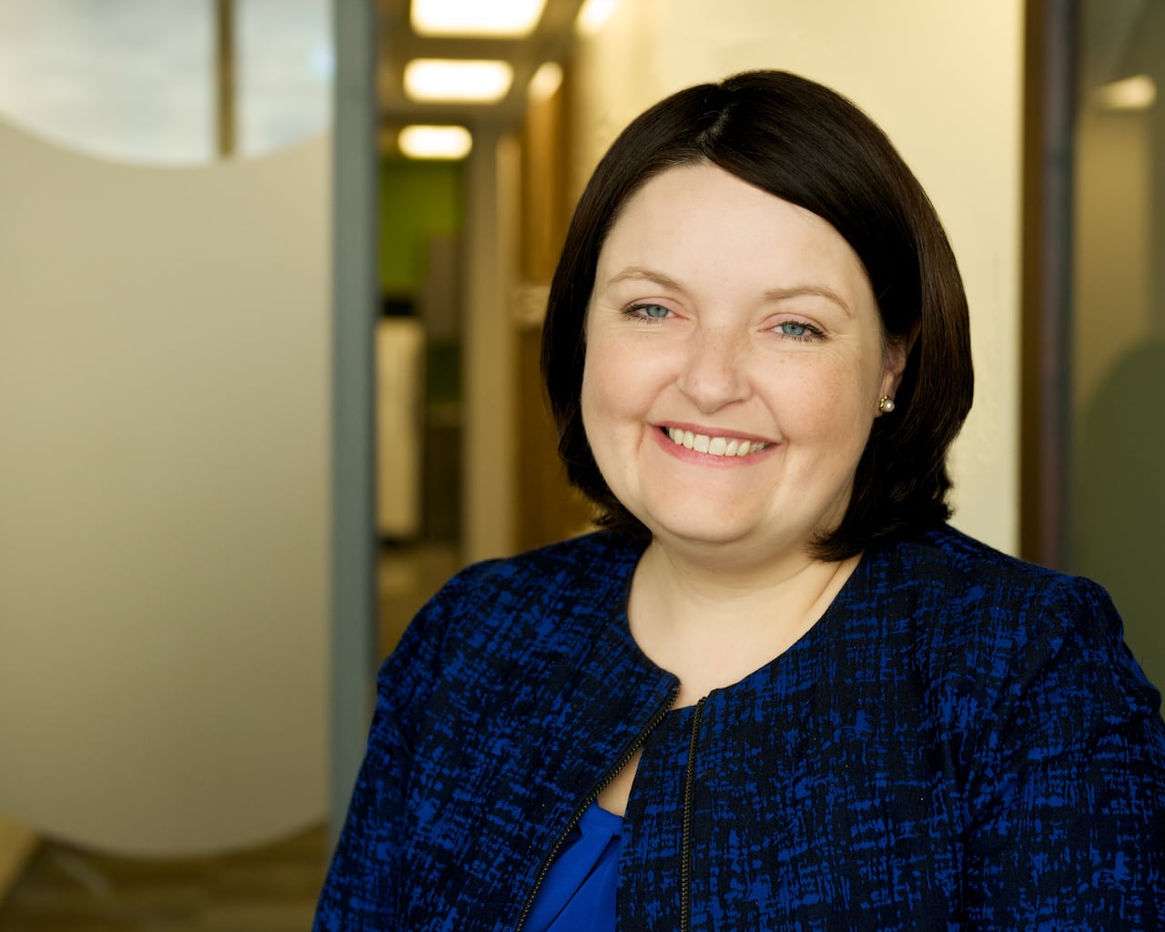 A woman in a blue blazer smiles at the camera. 