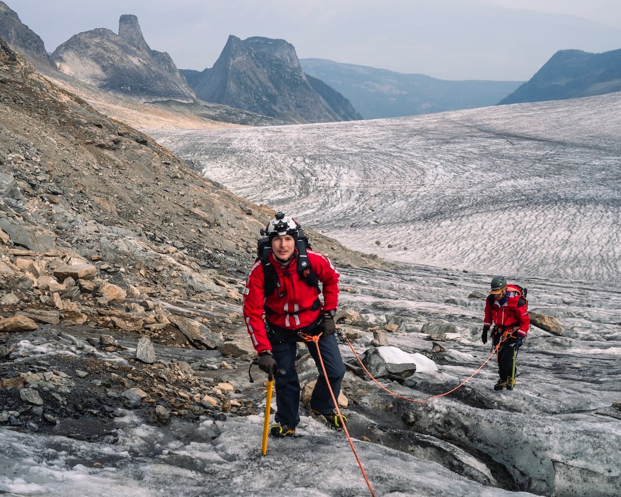 A man is on a line climbing a mountain.