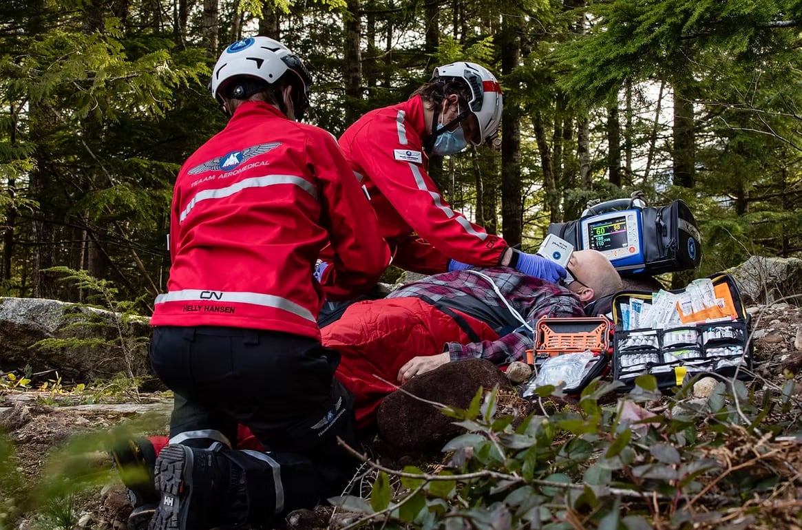Two people in red jackets simulate a rescue on a mountain.