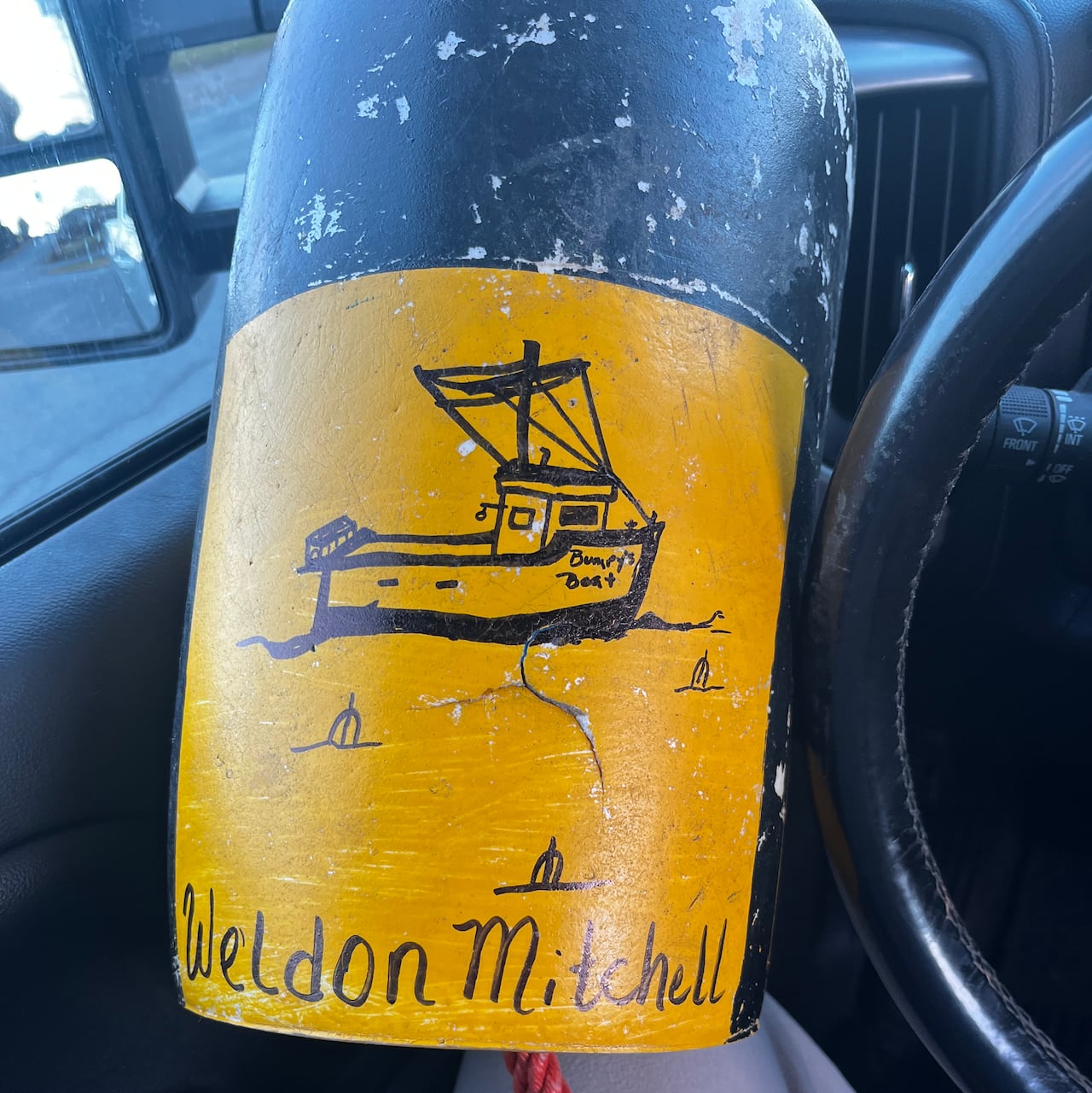A black and yellow buoy, decorated with a black marker. A boat is drawn on the buoy.