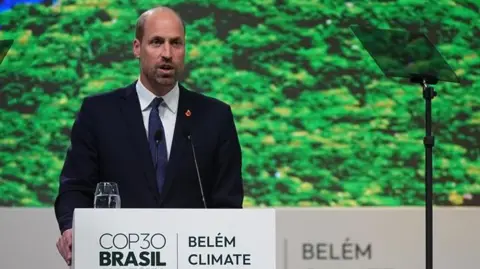 PA Media William stands at a podium bearing the words: COP30 Brasil Amazonian Belem Climate Summer. His right hand grips the podium as he speaks to the audience. He wears a dark suit, white shirt and tie and stands in front of an image of Amazonian-type forest.