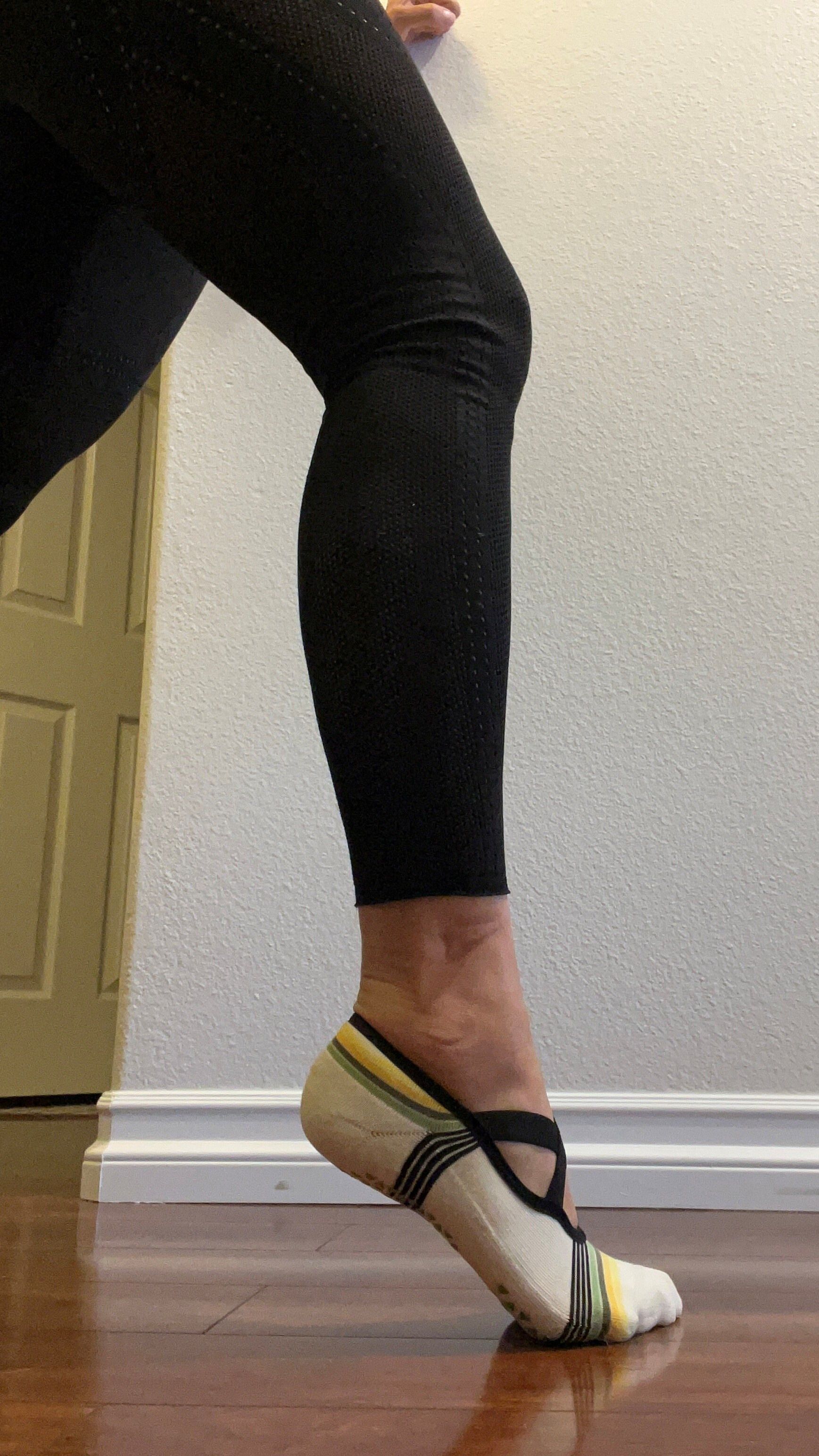 A leg in black leggings seen from the thigh down, with the heel raised