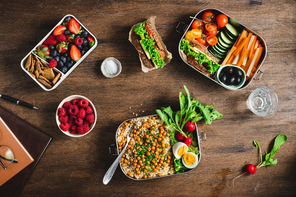 Top view of a healthy meal prep containers on wooden table. Cooked food with salad, fruits and berries in lunch boxes. flat lay. Food in boxes for school or office.