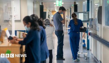 Health workers stand in a corridor in an NHS hospital.