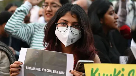 Getty Images A woman wearing a mask holds a poster during a protest on 9 November demanding the government take action to reduce air pollution in Delhi