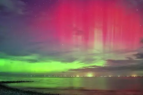 Ruth Davies | BBC Weather Watchers A mix of green and pink colours can be seen over the ocean.