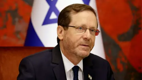 EPA-EFE/REX/Shutterstoc A man with short brown hair and glasses, in a navy suit, pictured in front of a white and blue Israeli flag with a star