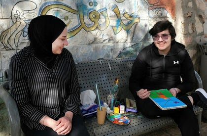 Haifa and Yamen. While we talk, Yamen's drawing progresses – he paints a sky and a field in vivid blue and green.