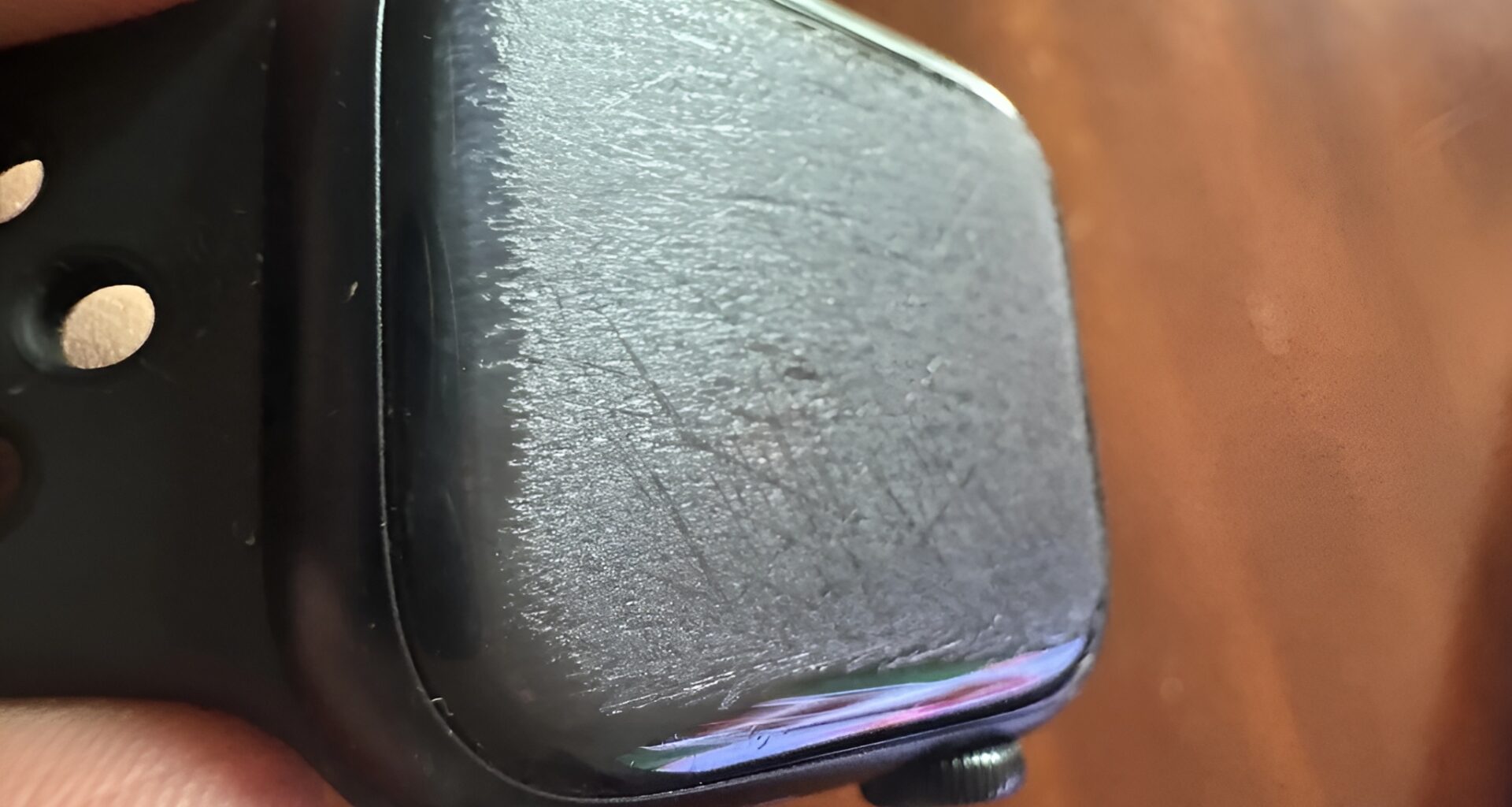 A close-up of a heavily scratched screen on an unbranded black smartwatch.