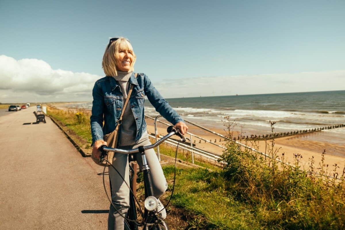 Woman riding her old fashioned bicycle along the Beach Esplanade at Aberdeen, Scotland.