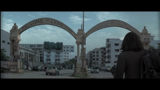 Ranveer Singh standing before the arched entrance to Lyari Town in Dhurandhar.
