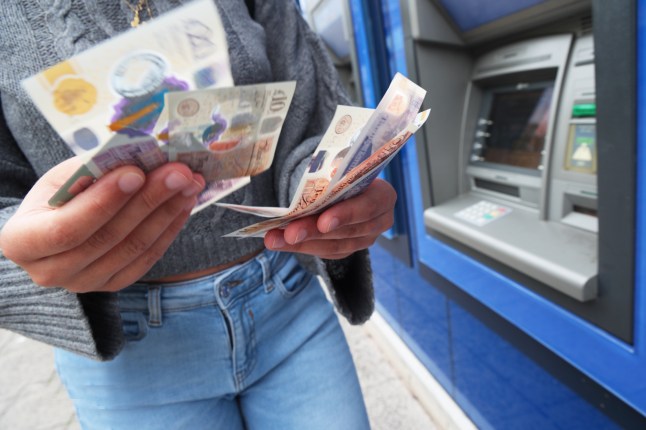 Woman taking cash out of UK cash machine