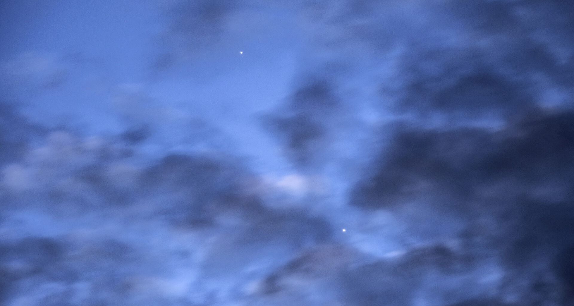 a photo of the sky at dawn with Mercury and Venus visible behind dark clouds