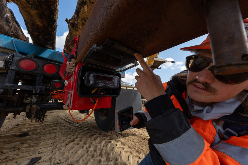 A Mast Reforestation employee checks the heavy equipment used for loading burned logs into the burial chamber on the Gentry ranch. Credit: Mast Reforestation