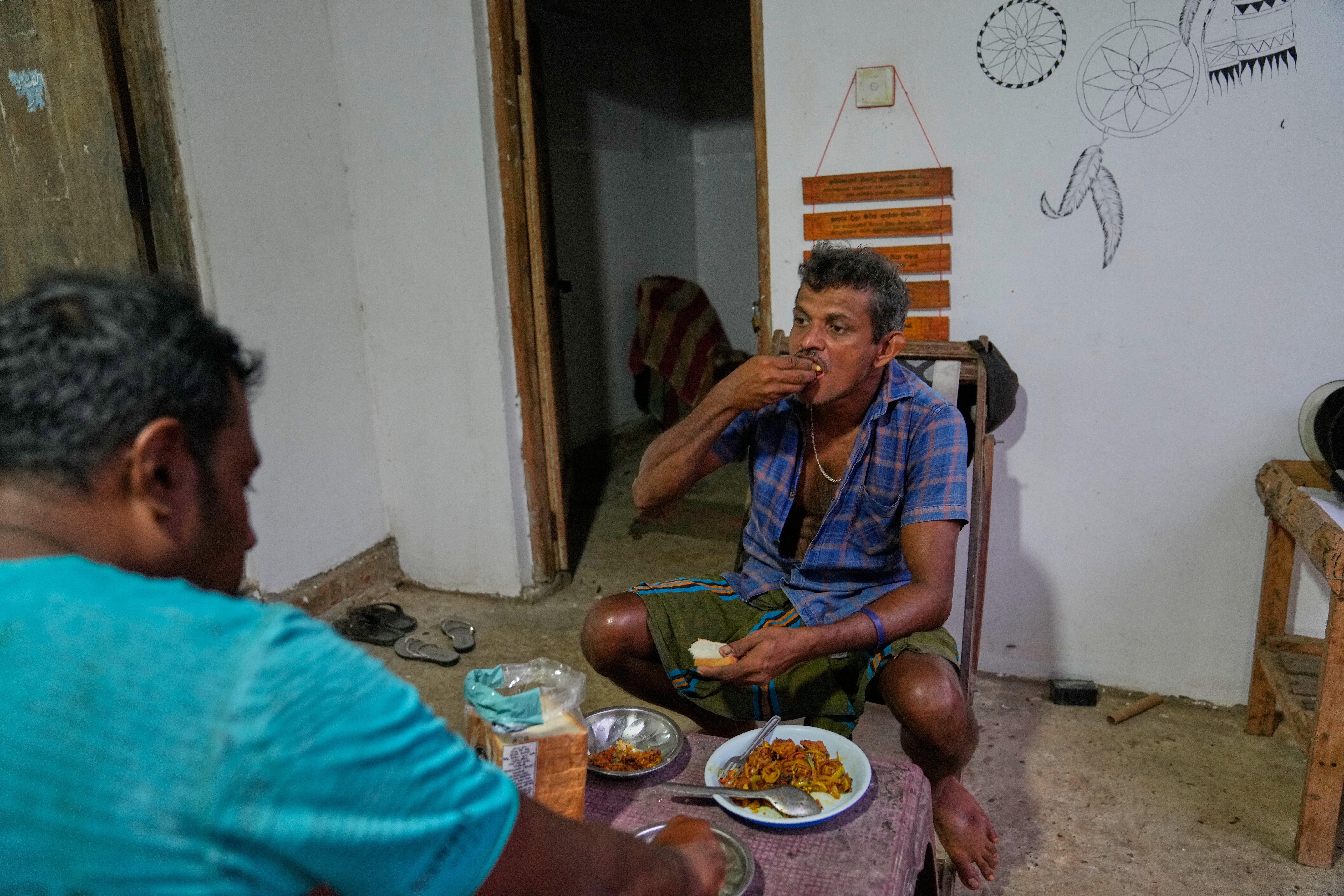 Ranjith Kumara, right, and Saman Kariyawasam eat giant snakehead fish in Walpaluwa, Sri Lanka