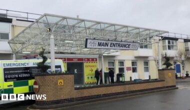 The main entrance to a hospital A&E department with an ambulance parked outside