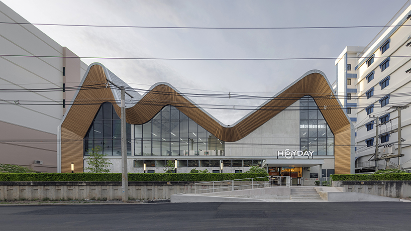 three asymmetrical curved gable roofs top ASWA’s community hub in thailand