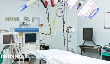 An empty bed in a hospital operating theatre surrounded by hospital equipment