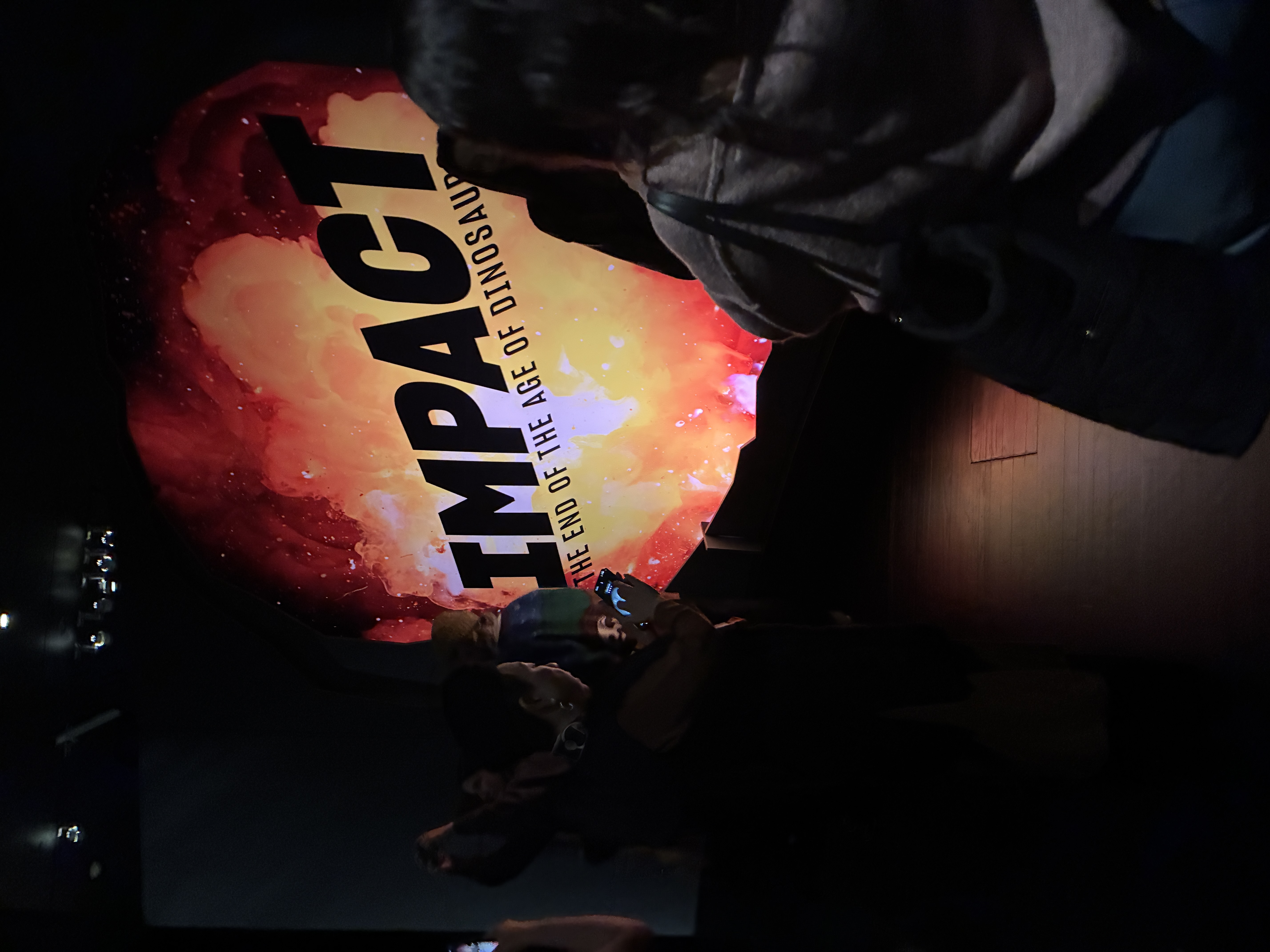 A lit up sign saying the word "Impact" in bold letters in a darkened room.