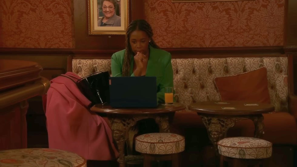 coronation street dee dee bailey in a green outfit working on a laptop in the rovers