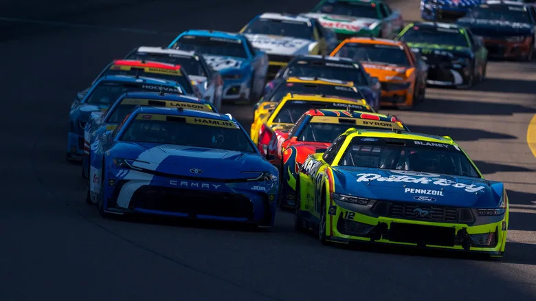 NASCAR race with cars bunched together on a turn