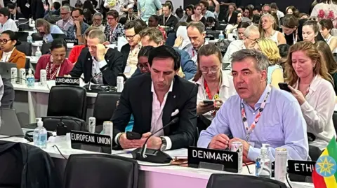 Tom Ingham/BBC Members of the EU negotiating team look ahead at the platform or check their phones during the critical plenary session at COP30