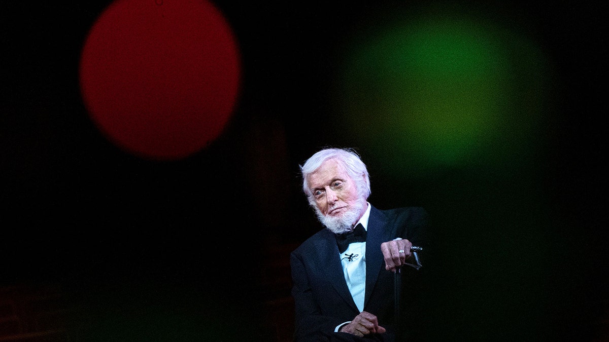 Dick Van Dyke on stage in a tux looking somber.