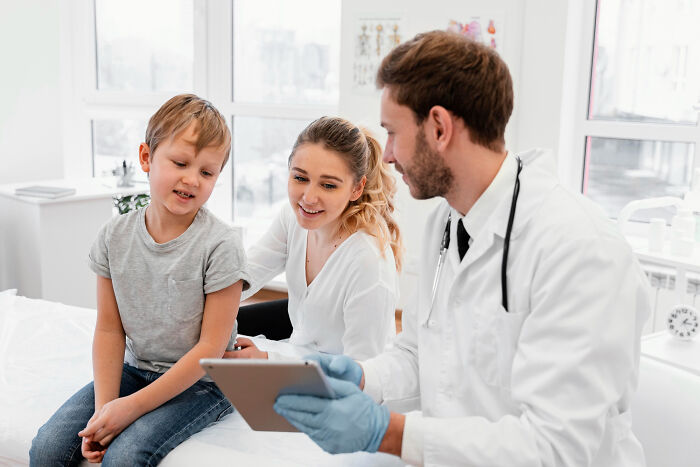 Doctor consulting a child and mother using a tablet, illustrating a real doctor versus Dr. Google medical discussion.